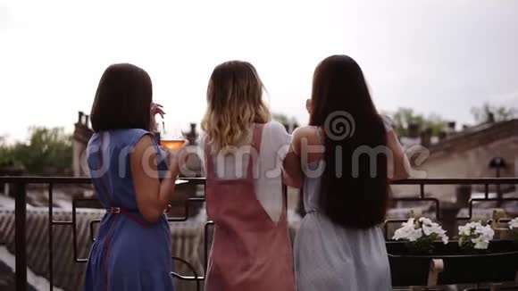三个女朋友在露台上享受母鸡聚会背面景色时髦现代的衣服美丽的城市景色视频的预览图