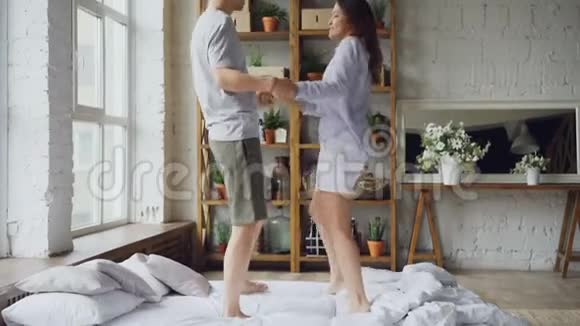 可爱的混血情侣穿着便服在床上跳舞谈笑风生享受快乐的时光视频的预览图