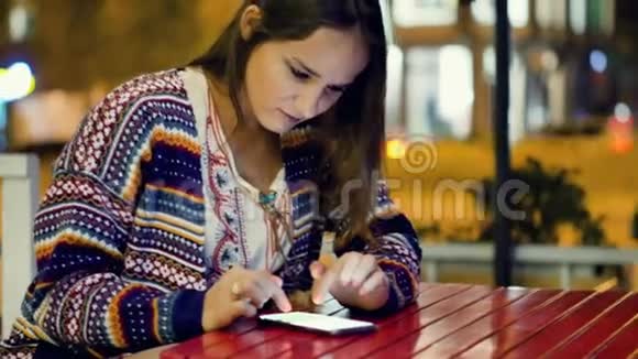 迷人的年轻女子写了一条信息晚上坐在一家街头咖啡馆的桌子旁视频的预览图