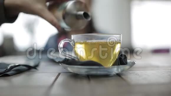 用绿茶盖住一个大的透明杯子妈妈倒进茶加糖在后台搅拌等待视频的预览图