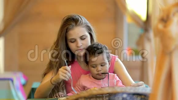 年轻的母女在咖啡馆里吃饭女儿喝柠檬水特写视频的预览图