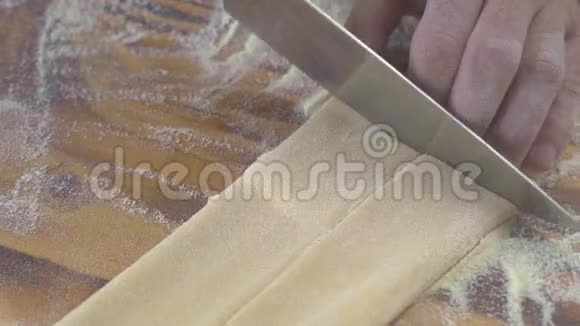男手在木板上用刀切自制面食面团厨师制作传统面食视频的预览图