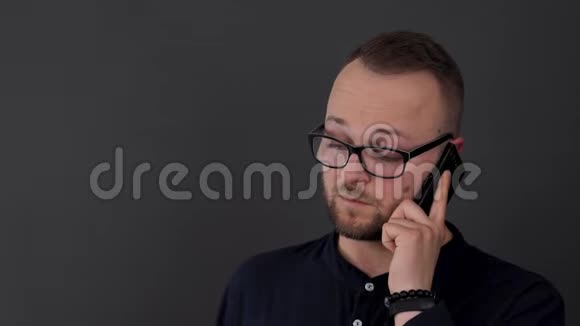 一个戴眼镜的留胡子的年轻人工作室拍摄的男性在黑色电话上说话同意一些事情视频的预览图