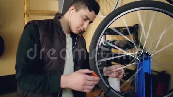 青年个体技工正在车间修理自行车轮年轻人穿着休闲服保暖背心和视频的预览图