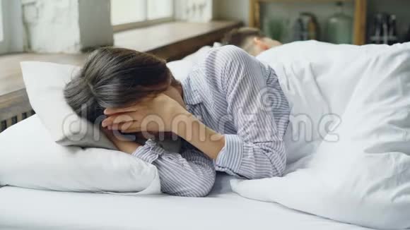 伤心的女人是睡衣躺在床上和躺在她身边背对着她的丈夫打架后哭泣视频的预览图