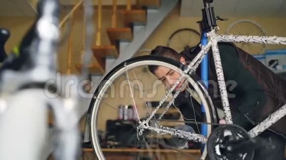 忙碌的服务人员正在检查后轮旋转踏板和看辐条同时修理自行车在工作室不错视频的预览图