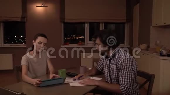男人和女人坐在桌子旁女孩在平板电脑上工作他拿着文件和女孩说话他既沮丧又不快乐男子视频的预览图