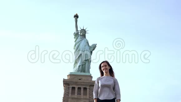 快乐微笑的欧洲女人站在镜头前在阳光明媚的纽约慢动作中向自由女神像摆姿势视频的预览图