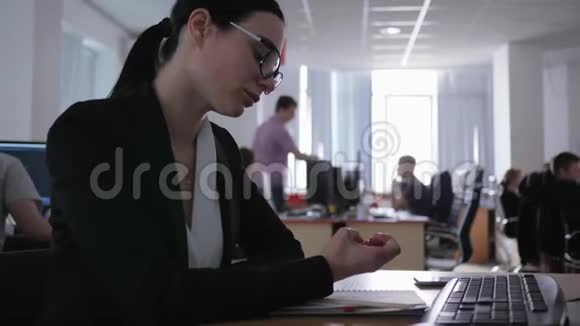 无聊的商务女性坐在办公室特写的办公桌前看着自己视频的预览图