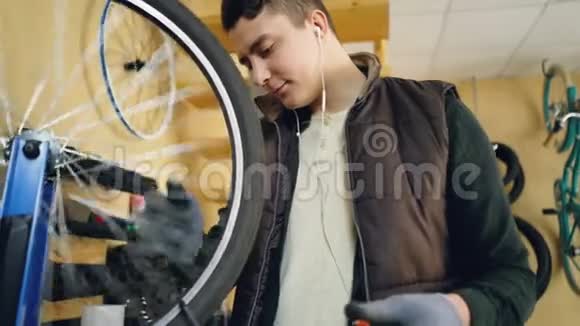 集中的机械师正在看旋转自行车车轮检查辐条然后用工具校直它们年轻人视频的预览图
