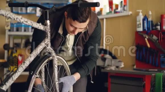 有经验的手套和背心男主人正在用特殊工具固定自行车轮调整它并拧紧接头视频的预览图