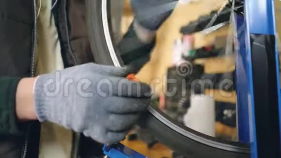 男手在油腻手套中的特写镜头旋转破碎的自行车轮和用工具矫直弯曲的辐条工作视频的预览图