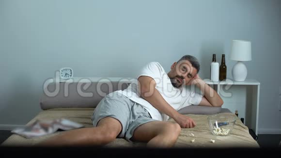 男人在电视机前吃爆米花睡着单身汉消极生活视频的预览图