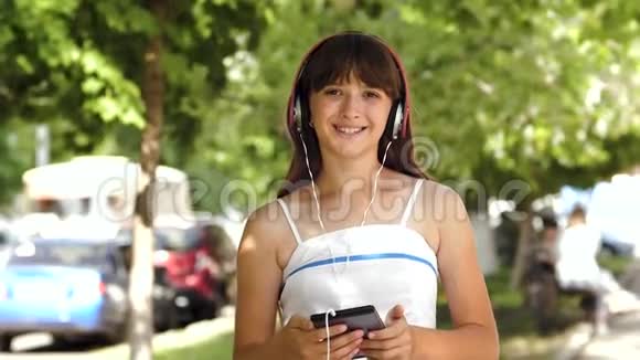 戴着平板耳机的女孩在城市里微笑视频的预览图
