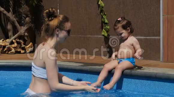 妈妈和小女儿在开放的游泳池里玩耍视频的预览图