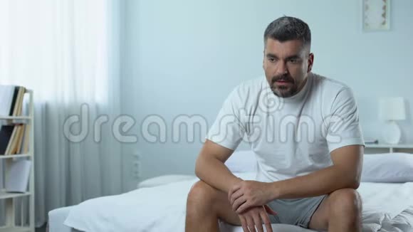 悲伤的失业男人坐在卧室里想着未来抑郁的计划视频的预览图
