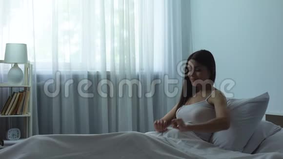 女士在舒适的骨科床垫上享受甜蜜健康睡眠后伸展身体视频的预览图