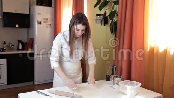 穿围裙的女孩准备生披萨面团这个女孩正在家里准备一个美味的披萨糕点视频的预览图
