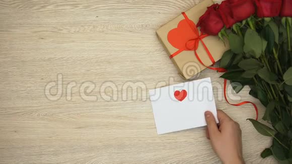 男士将信封放在靠近玫瑰和礼品盒的木桌上视频的预览图