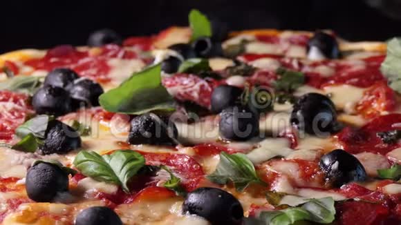 烤披萨配意大利香肠黑橄榄罗勒和莫扎雷拉奶酪旋转射击视频的预览图