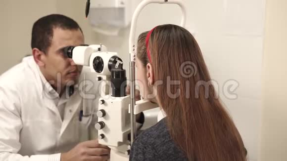男性眼科医生正在一家医疗机构检查年轻女性的眼睛视频的预览图