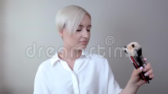 一个留着短发的金发女孩正在为日常化妆选择合适的画笔视频的预览图
