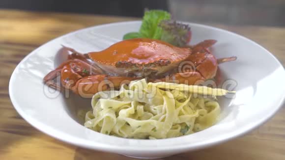 意大利海产面食用红蟹和鲜草调味放在木桌上的白色盘子里提供传统面食视频的预览图