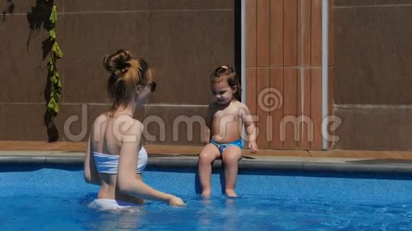 妈妈和小女儿在开放的游泳池里玩耍视频的预览图