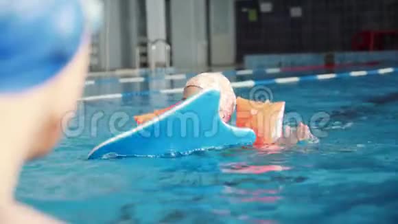 一个小女孩在哥哥的监督下在游泳池里游泳视频的预览图