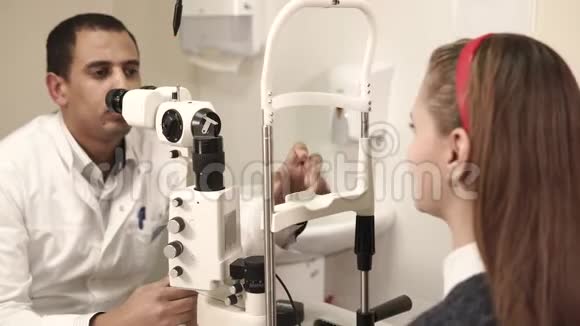 一个十几岁的少年在一个眼科医生的诊所里把头放在基座上检查他的视力视频的预览图