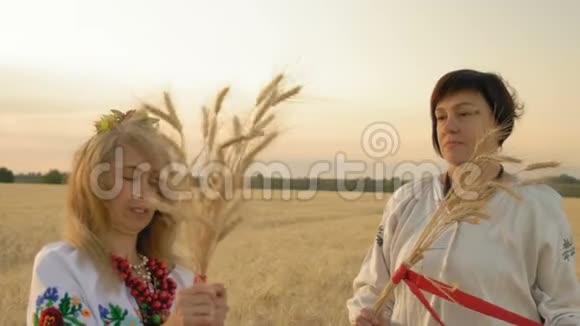 慢动作两名女性穿着全国服装用红麦穗带扎染麦田视频的预览图