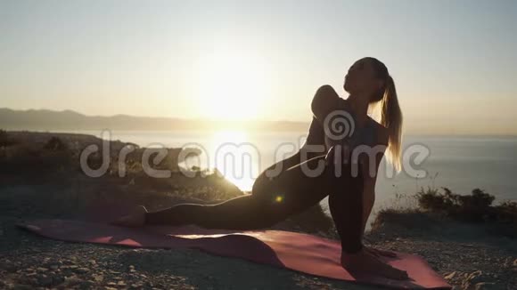 女性在垫子上练习瑜伽日出时伸展身体动作缓慢视频的预览图