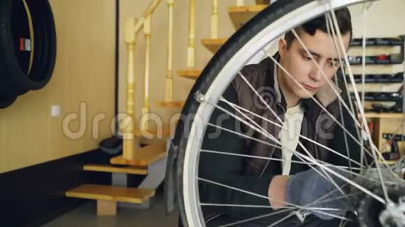 有经验的年轻人正在用扳手和工具固定自行车轮木制小型舒适的车间内部视频的预览图