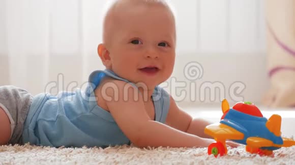 孩子在家玩玩具可爱的小男孩穿着睡衣在地板上爬行玩玩具视频的预览图
