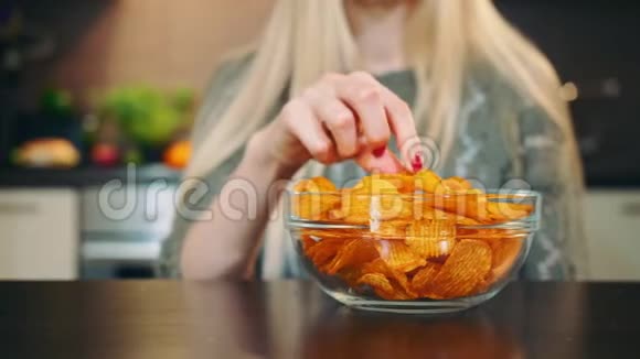 很高兴女人吃薯片美丽的年轻女性一边吃薯片一边看着摄像机视频的预览图