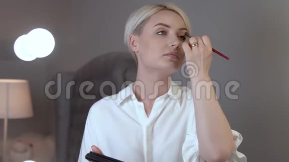 镜头从一个短头发的金发女人移开在他的眼皮上投下一个眼影视频的预览图