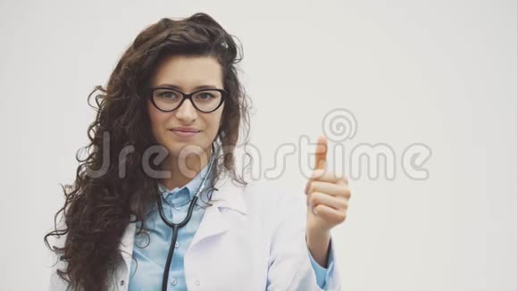 幸福的年轻微笑女孩医生的肖像穿着白色长袍平躺着一只手笔直向前伸进去视频的预览图