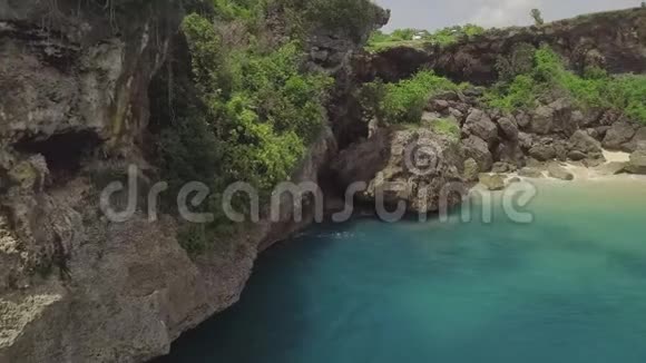 岩石海岸的空中景观悬崖美丽的蓝色海浪在海岸的岩石悬崖上飞溅青绿色海洋视频的预览图