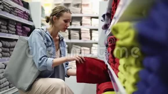 白种人女人从排里挑选毛巾商店里的货架上堆满了各种毛巾视频的预览图