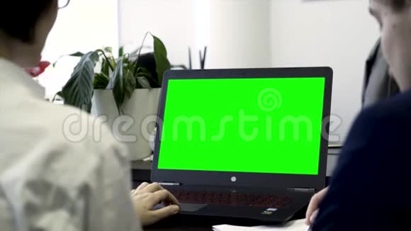 年轻女性在办公室工作坐在电脑前的椅子上屏幕绿色后视两名女同事视频的预览图
