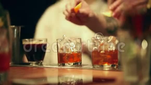 酒保在工作在杯子里的酒精鸡尾酒中加入装饰元素视频的预览图