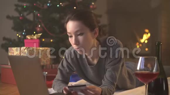 女孩在圣诞树附近通过信用卡在线购买礼物视频的预览图