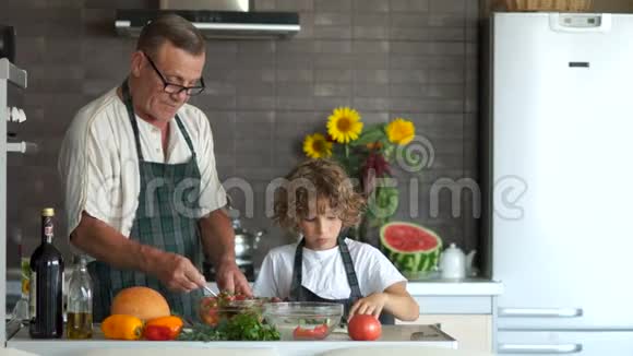 孙子在菜板上切黄瓜做沙拉祖父告诉他一些事传授烹饪技巧视频的预览图