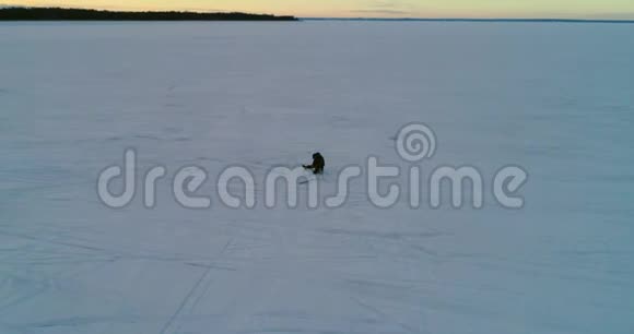 孤独的渔夫坐在结冰的河上的洞前晚上4K视频的预览图