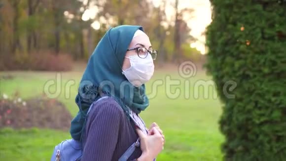 戴着头巾的阿拉伯学生戴着眼镜在公园里用医用绷带视频的预览图