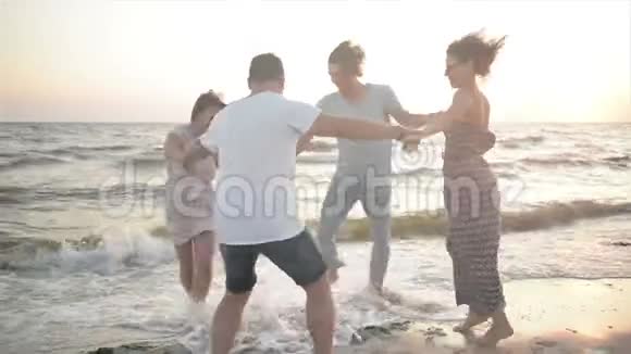 在风和日丽的日子里四个快乐的朋友在海桦上的圆圈里跳舞视频的预览图