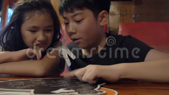 快乐的亚洲孩子在咖啡馆或餐馆选择一份饮料和食物的菜单视频的预览图