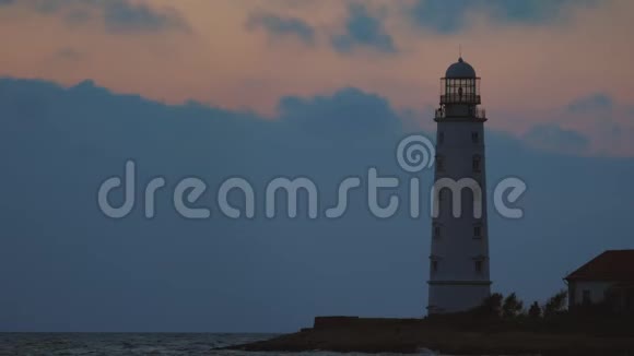 海岸上一座白色的大灯塔发出黄光视频的预览图