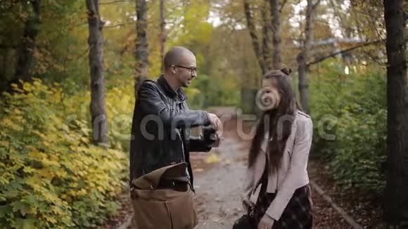 一位摄影师在秋天公园给一个十几岁的女孩拍照视频的预览图