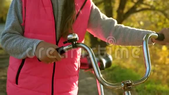 女孩的手拿着弯曲的自行车把手特写镜头女孩在秋天骑自行车在公园里散步视频的预览图